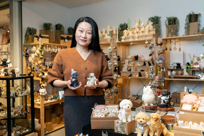Person holding two figurines in a store filled with various animal figurines and ornaments.